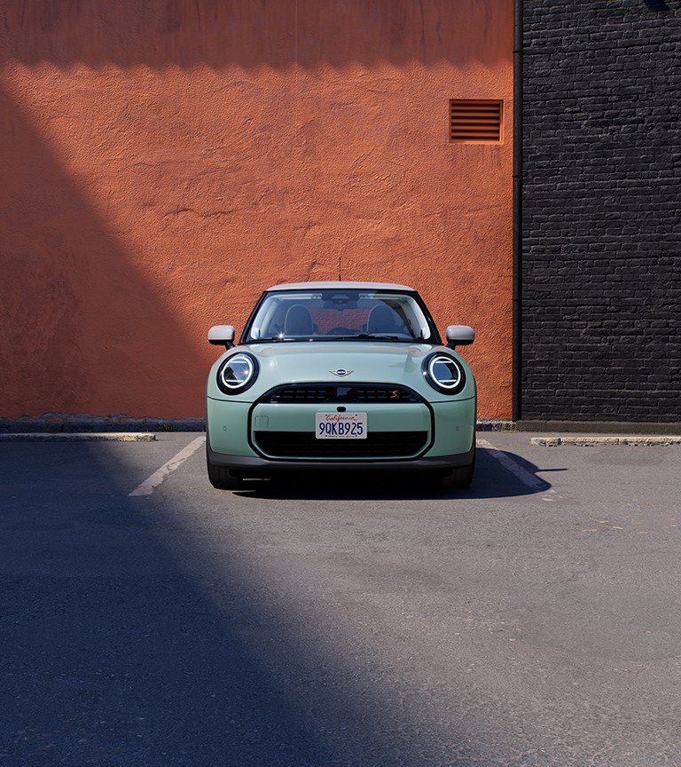 MINI Cooper visto de frente, estacionado em frente a uma parede laranja e preta 